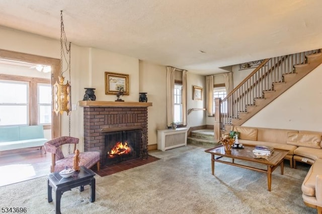 carpeted living room with stairway, a healthy amount of sunlight, and a fireplace