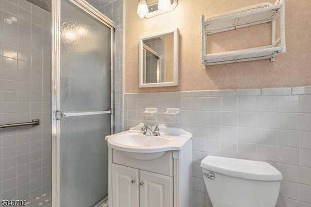 bathroom featuring vanity, tile walls, a shower stall, and toilet