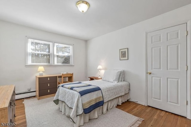 bedroom with a baseboard heating unit and wood finished floors