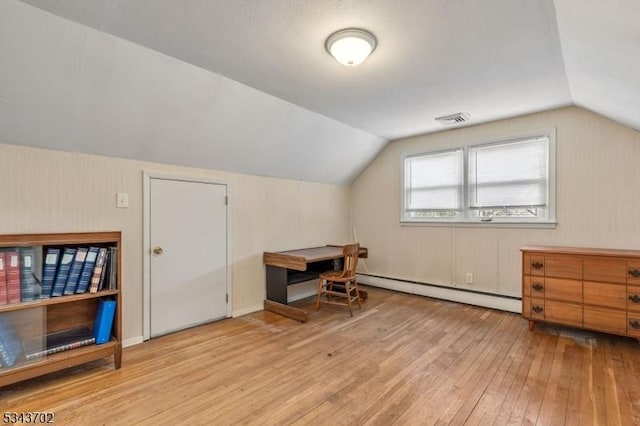 additional living space with visible vents, a baseboard heating unit, lofted ceiling, and hardwood / wood-style flooring