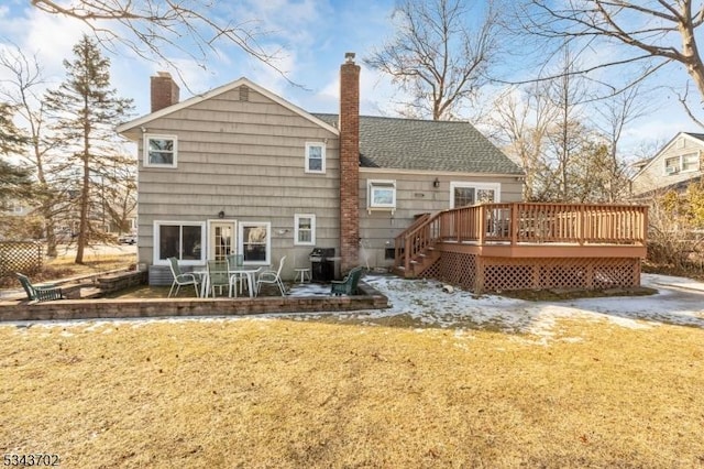 back of property with roof with shingles, a chimney, a deck, a patio area, and a lawn