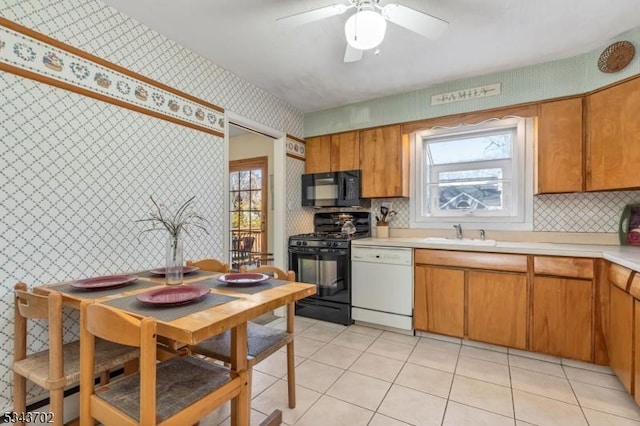 kitchen featuring light tile patterned floors, wallpapered walls, a sink, black appliances, and light countertops