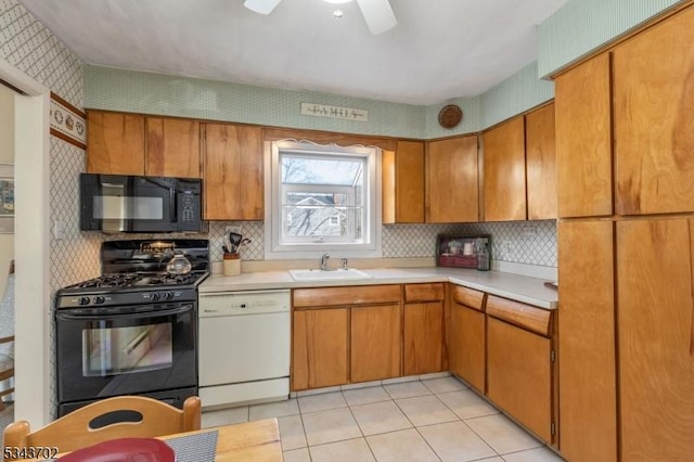 kitchen with light tile patterned floors, wallpapered walls, a sink, black appliances, and light countertops