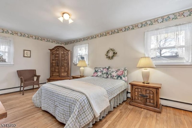 bedroom featuring a baseboard radiator, multiple windows, and light wood-style flooring