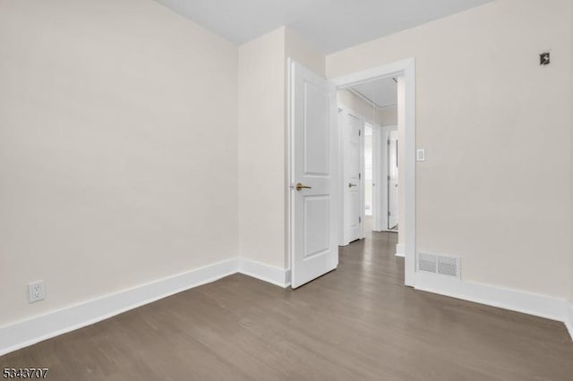 unfurnished room with attic access, baseboards, visible vents, and dark wood-type flooring