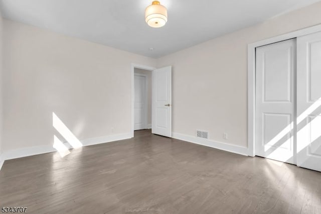 empty room featuring visible vents, wood finished floors, and baseboards