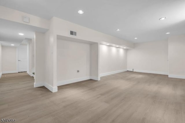 below grade area featuring recessed lighting, visible vents, light wood-style flooring, and baseboards