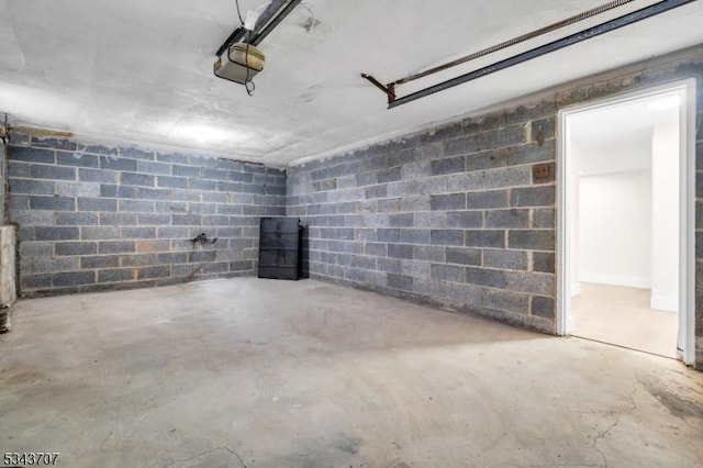 garage featuring concrete block wall and a garage door opener