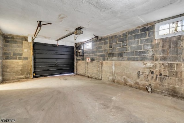 garage featuring a garage door opener and concrete block wall