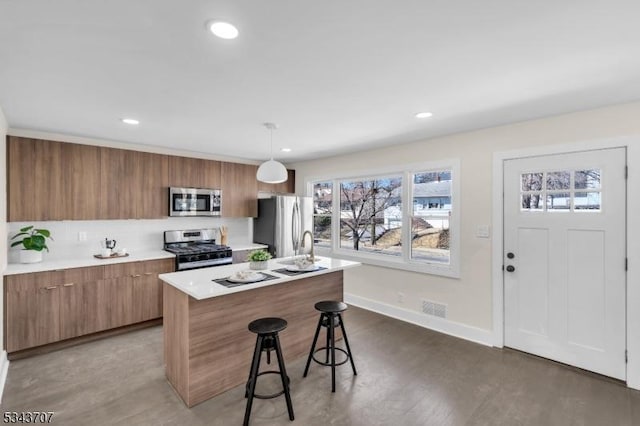 kitchen with visible vents, brown cabinets, a breakfast bar, appliances with stainless steel finishes, and light countertops