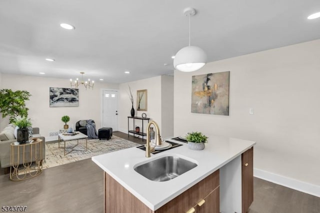 kitchen with open floor plan, a center island with sink, light countertops, recessed lighting, and a sink