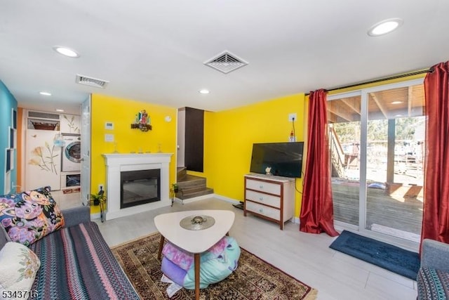 living room with a glass covered fireplace, washer / clothes dryer, recessed lighting, and visible vents