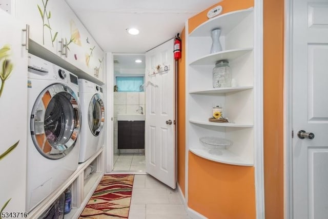 laundry area featuring light tile patterned floors, washing machine and clothes dryer, cabinet space, recessed lighting, and a sink