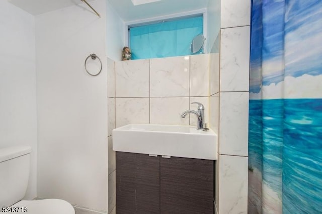 bathroom with tile walls, toilet, vanity, and a shower with curtain