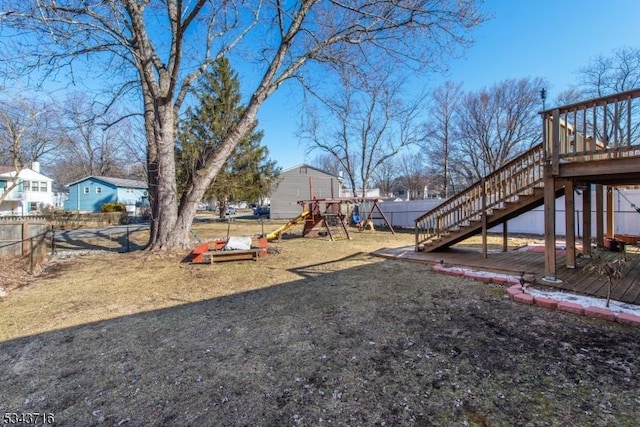 view of yard with a wooden deck, a playground, stairs, and fence