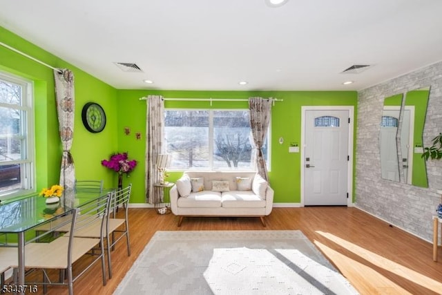 sitting room with visible vents, wood finished floors, and an accent wall