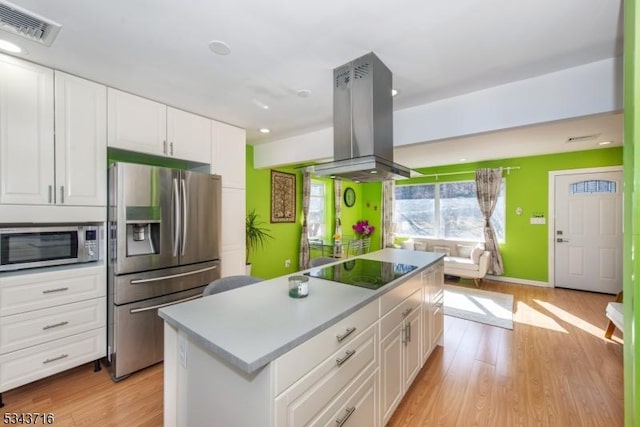 kitchen with light wood-style floors, island exhaust hood, visible vents, and stainless steel appliances