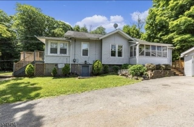 rear view of property with stairway, a yard, and a sunroom