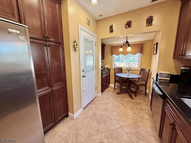 kitchen with light tile patterned floors, baseboards, stainless steel appliances, hanging light fixtures, and dark countertops