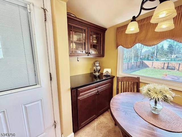 kitchen with dark countertops, light tile patterned floors, and glass insert cabinets