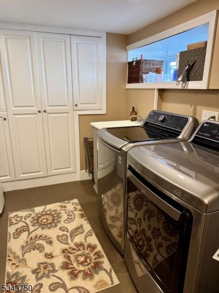 washroom featuring cabinet space and washing machine and clothes dryer