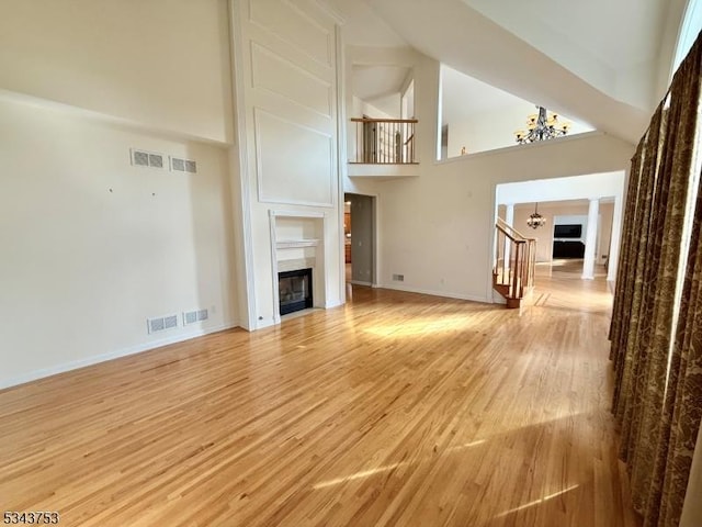 20 Tonnelier Way, Denville Twp, NJ 07834 - unfurnished living room featuring a fireplace, a chandelier, high vaulted ceiling, stairs, and light wood-style floors