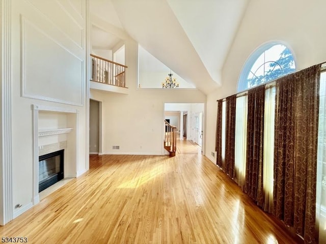 20 Tonnelier Way, Denville Twp, NJ 07834 - unfurnished living room with high vaulted ceiling, wood finished floors, a fireplace, a chandelier, and stairs