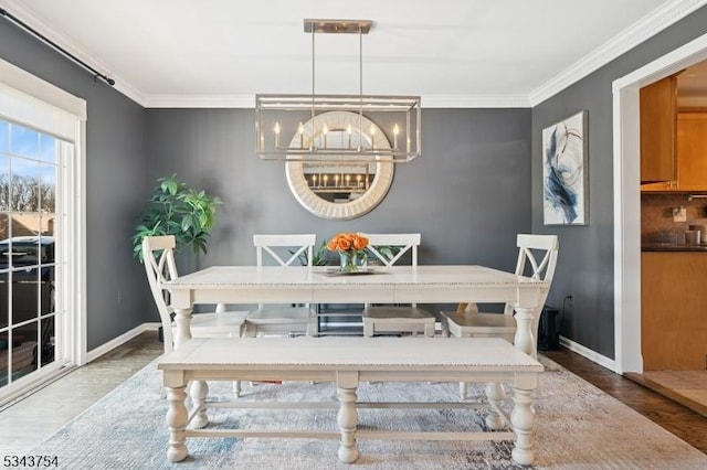 dining room featuring baseboards, wood finished floors, an inviting chandelier, and ornamental molding