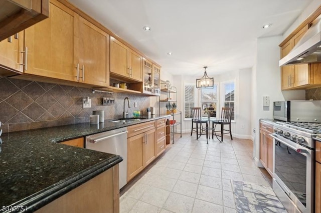 kitchen featuring a sink, under cabinet range hood, appliances with stainless steel finishes, decorative backsplash, and a chandelier