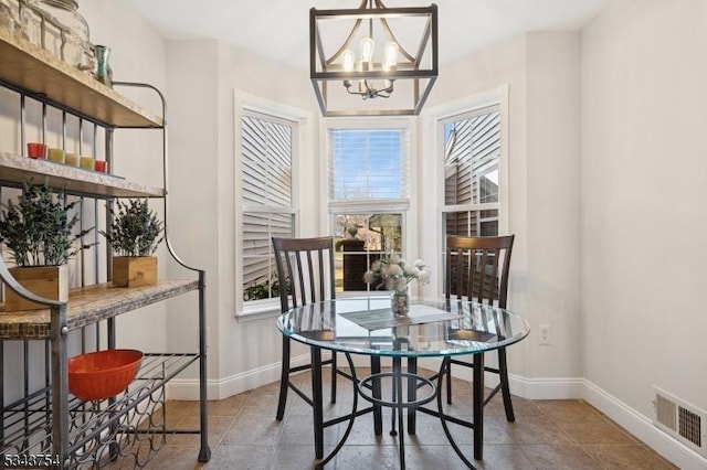 dining space with tile patterned floors, visible vents, baseboards, and an inviting chandelier