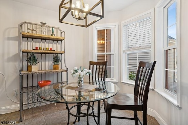 dining space featuring baseboards, a notable chandelier, and dark tile patterned flooring