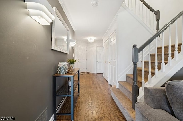 interior space with visible vents, ornamental molding, wood finished floors, baseboards, and stairs