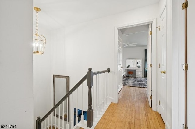 hall featuring an upstairs landing, a chandelier, and light wood finished floors