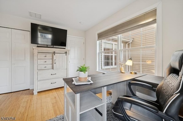 office with light wood-style flooring and visible vents