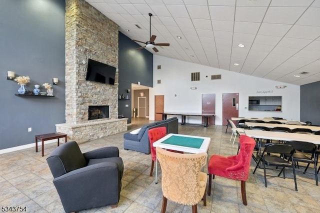 living room featuring a stone fireplace, baseboards, visible vents, and ceiling fan