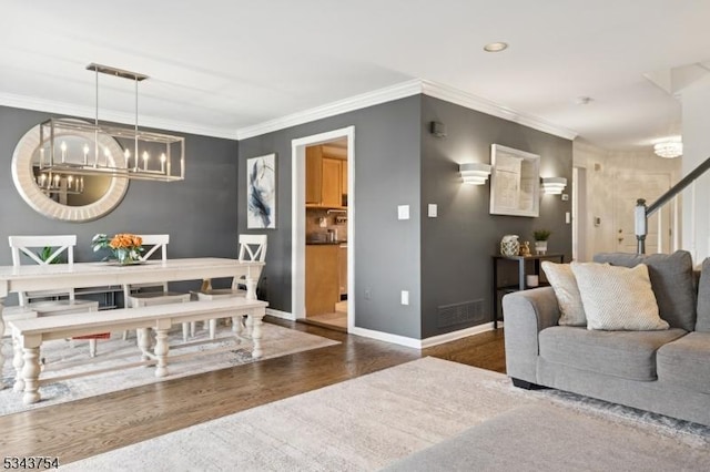 dining space featuring visible vents, baseboards, ornamental molding, wood finished floors, and a notable chandelier