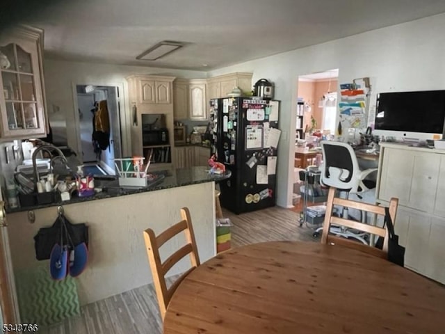 kitchen with a peninsula, light wood-style flooring, freestanding refrigerator, cream cabinetry, and glass insert cabinets