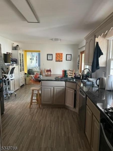 kitchen with a peninsula, a breakfast bar area, dark wood-type flooring, and a sink