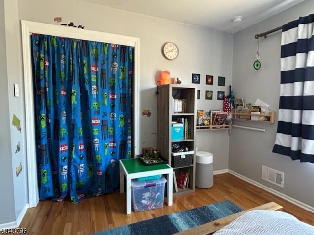 bedroom featuring visible vents, baseboards, and wood finished floors