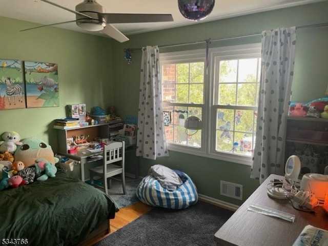 bedroom with a ceiling fan, wood finished floors, and visible vents