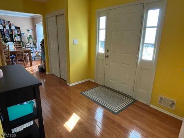 foyer entrance featuring a wealth of natural light, visible vents, and wood-type flooring