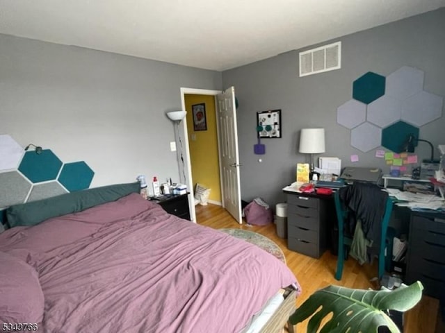 bedroom with light wood-style floors and visible vents