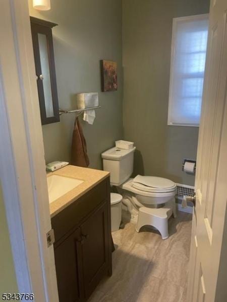 half bathroom with vanity, toilet, and wood finished floors