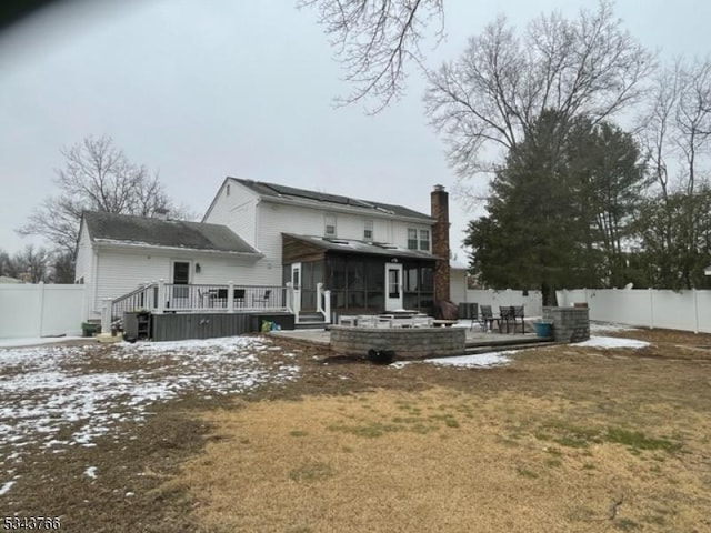 snow covered back of property with a patio, a fenced backyard, and a wooden deck