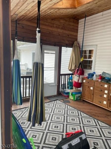 game room featuring lofted ceiling, wooden walls, wood ceiling, and wood finished floors