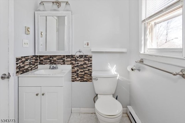 half bath with tile patterned floors, toilet, baseboard heating, and vanity