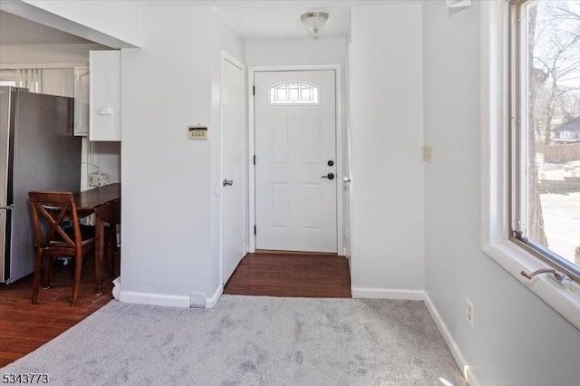 doorway with baseboards, carpet floors, and wood finished floors