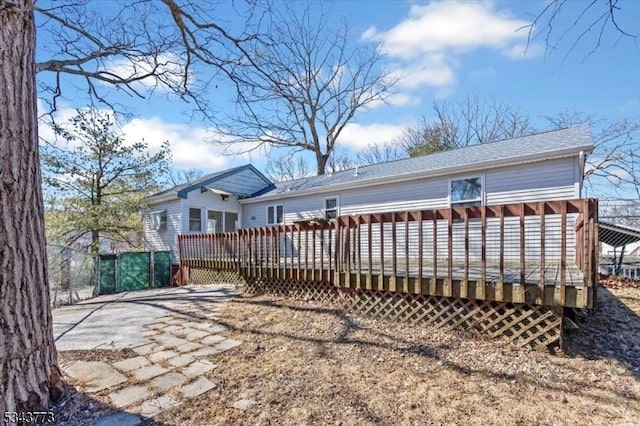 rear view of house featuring a wooden deck and a shingled roof