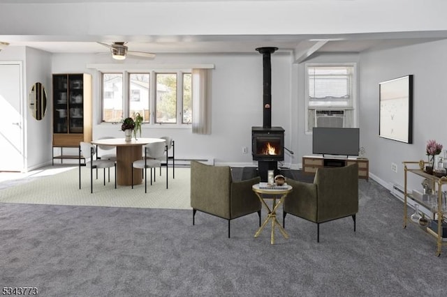 carpeted living room with a wood stove, cooling unit, a ceiling fan, and baseboards