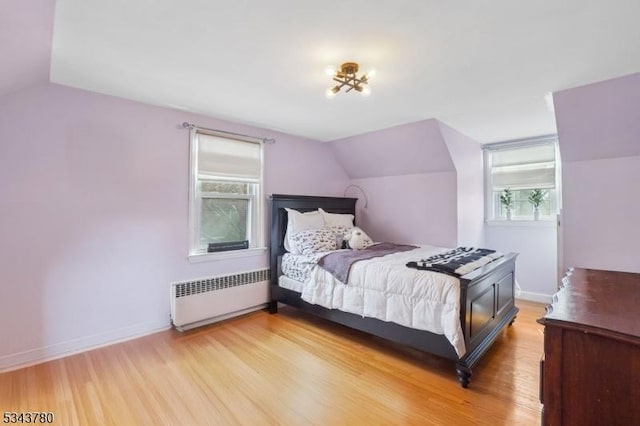 bedroom with lofted ceiling, light wood-style flooring, radiator heating unit, and baseboards